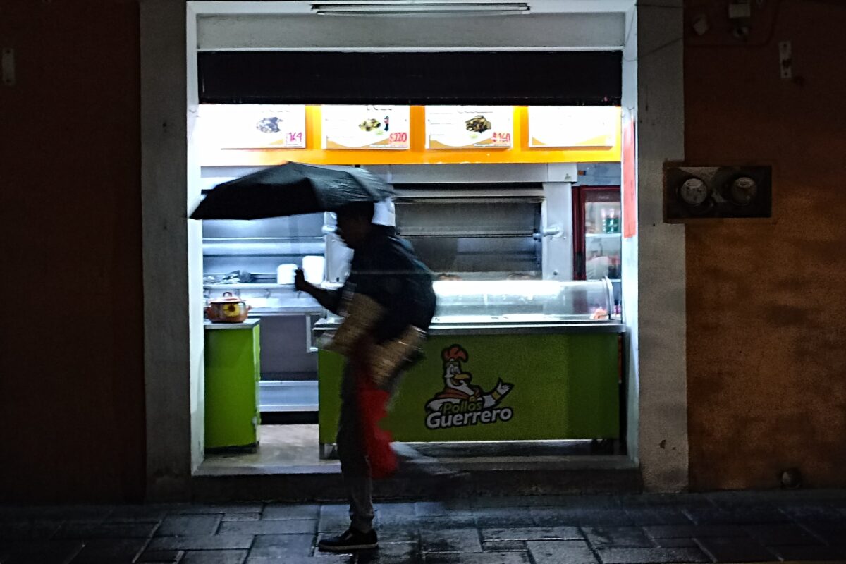 Ciudadanos caminan bajo la lluvia está noche por calles del centro histórico de la capital de Tlaxcala